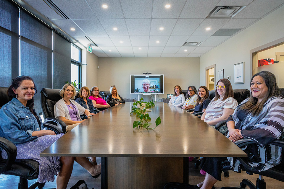 A group of people sit at a table, smiling at the camera