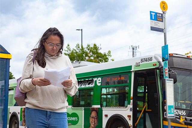 A girl standing at a bus stop.
