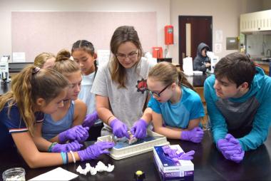 Group of children gathered around a science experiment with an adult