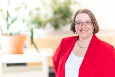 Dr. Elizabeth Saewyc in modern background with a pot of plants