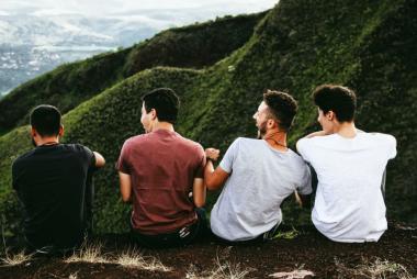 Four men sit together facing away from the camera