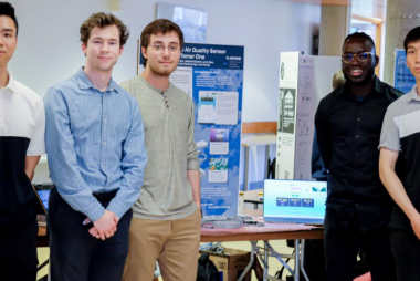 IoT ECE team standing around their presentation. 