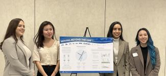 Four women presenting an easel board titled "Moving beyond the Car"