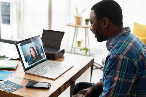 Man sitting at home and engaging with woman in online meeting