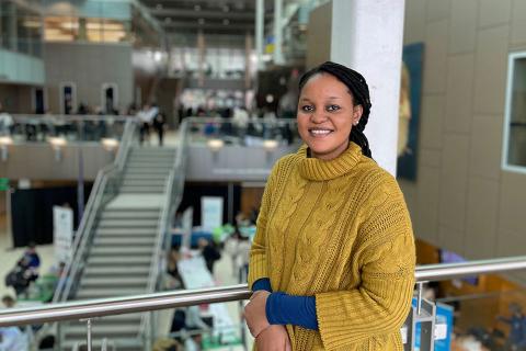 Chadia Uwamahoro in a yellow sweater, smiling at camera