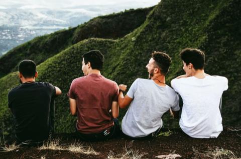 Four men sit together facing away from the camera