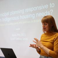 Woman in orange sweater at lectern